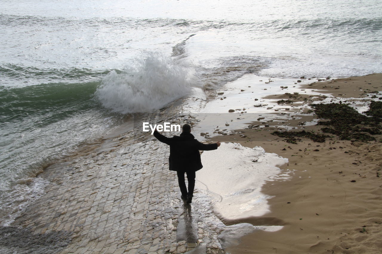 Rear view of man walking on shore