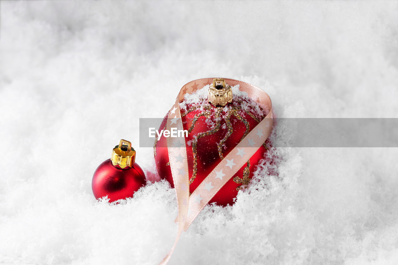 Close-up of red christmas ornaments on snow