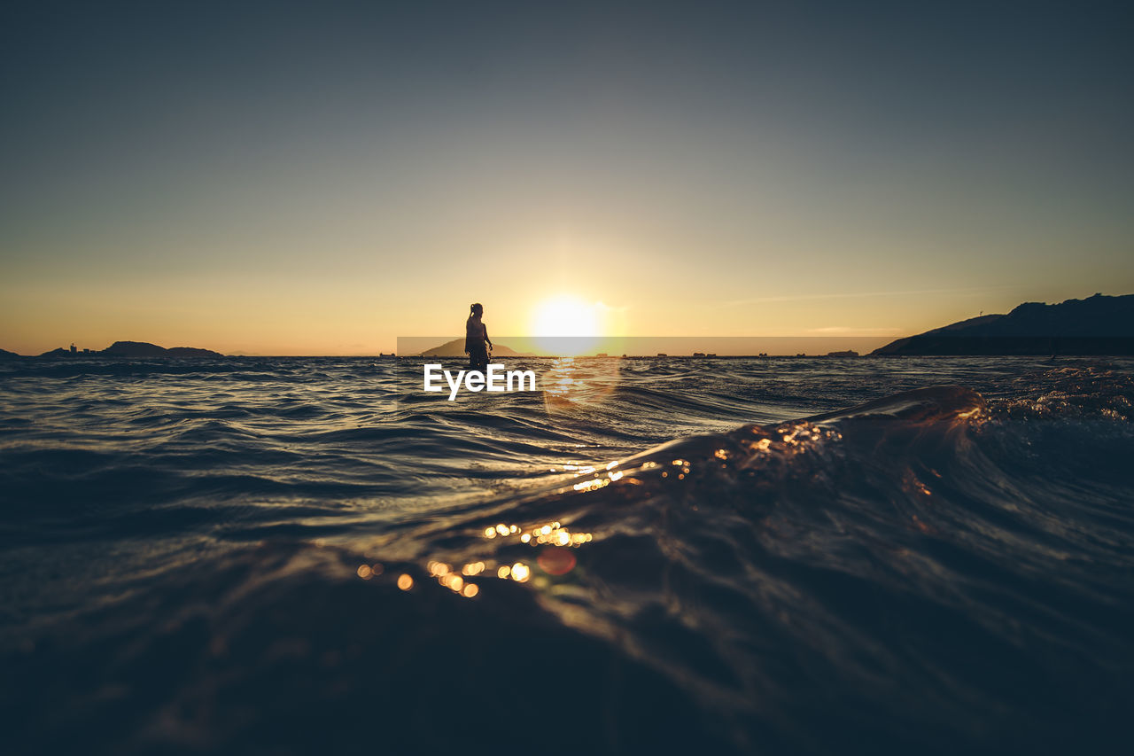 Scenic view of one person in sea at sunset