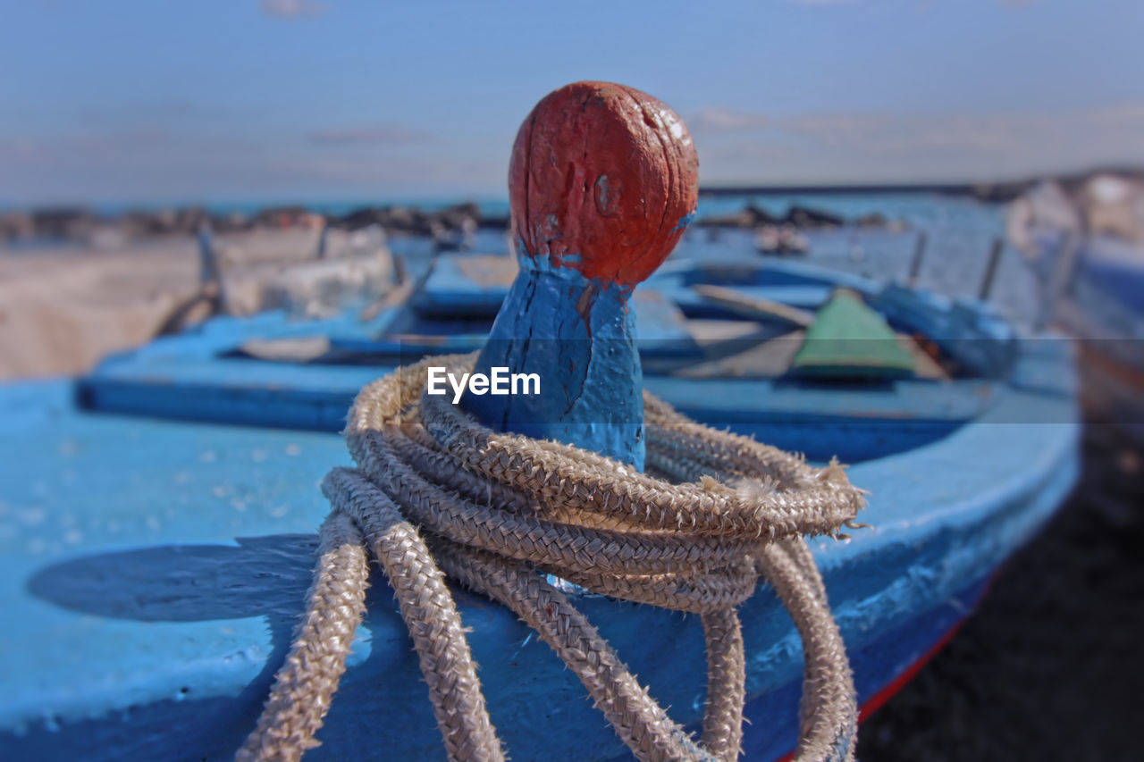 Close-up of rope tied to fishing net on beach