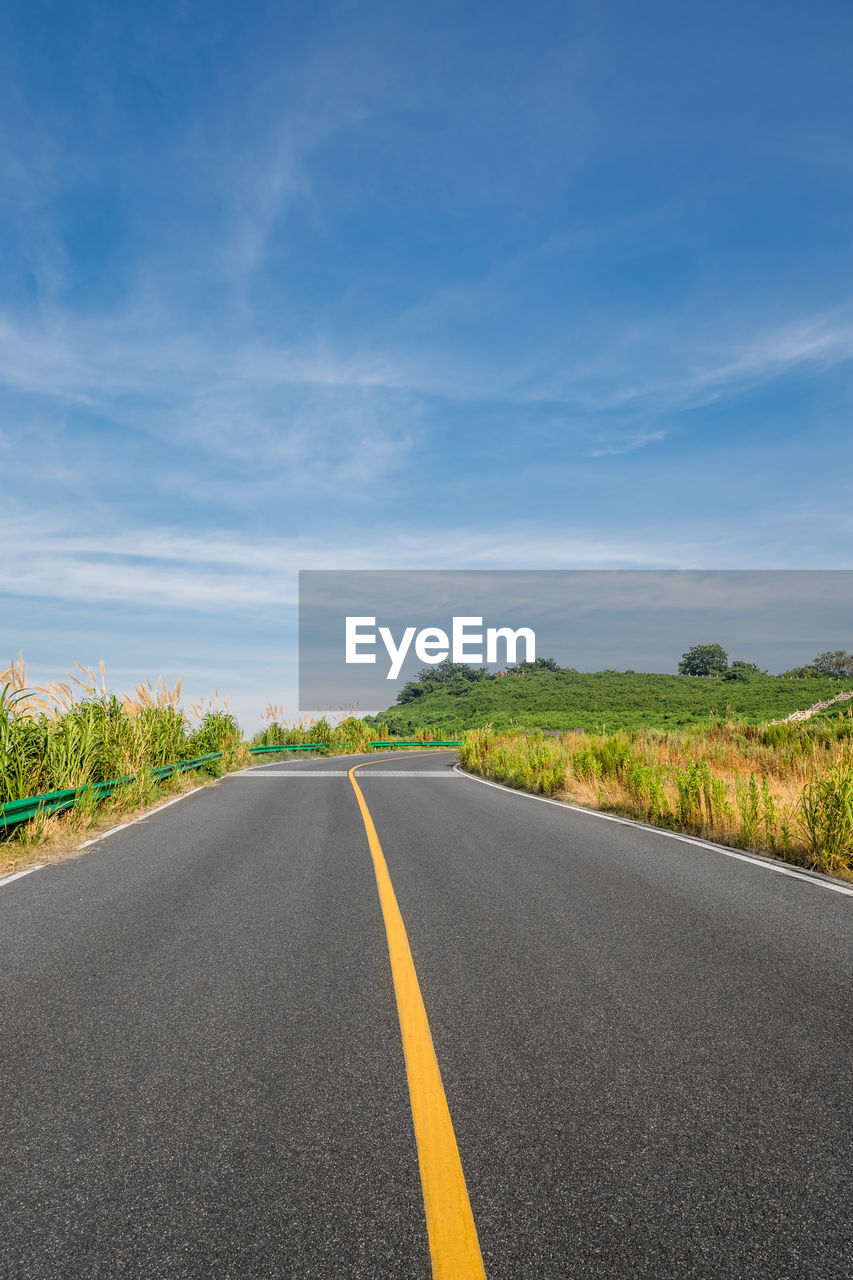 SURFACE LEVEL OF EMPTY ROAD ALONG COUNTRYSIDE LANDSCAPE