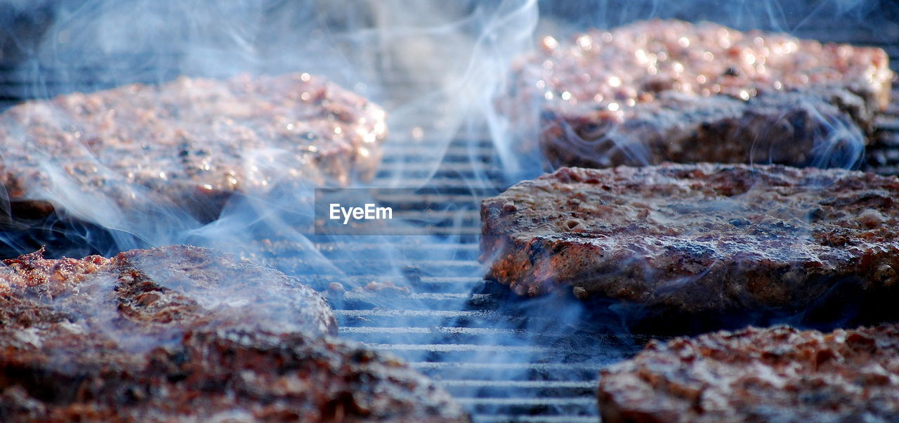 Hamburgers on an open grill outdoors.