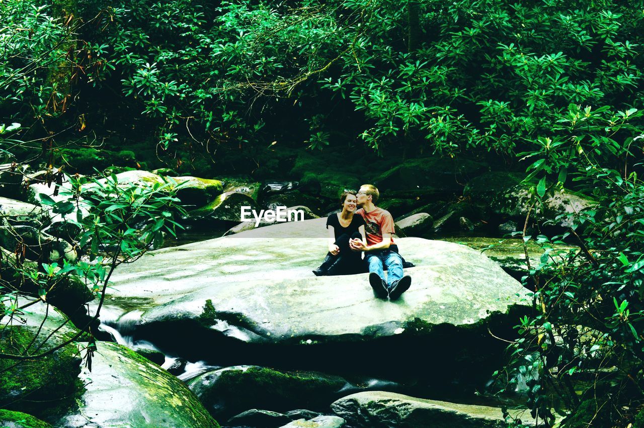 FULL LENGTH OF YOUNG WOMAN ON ROCK AT FOREST