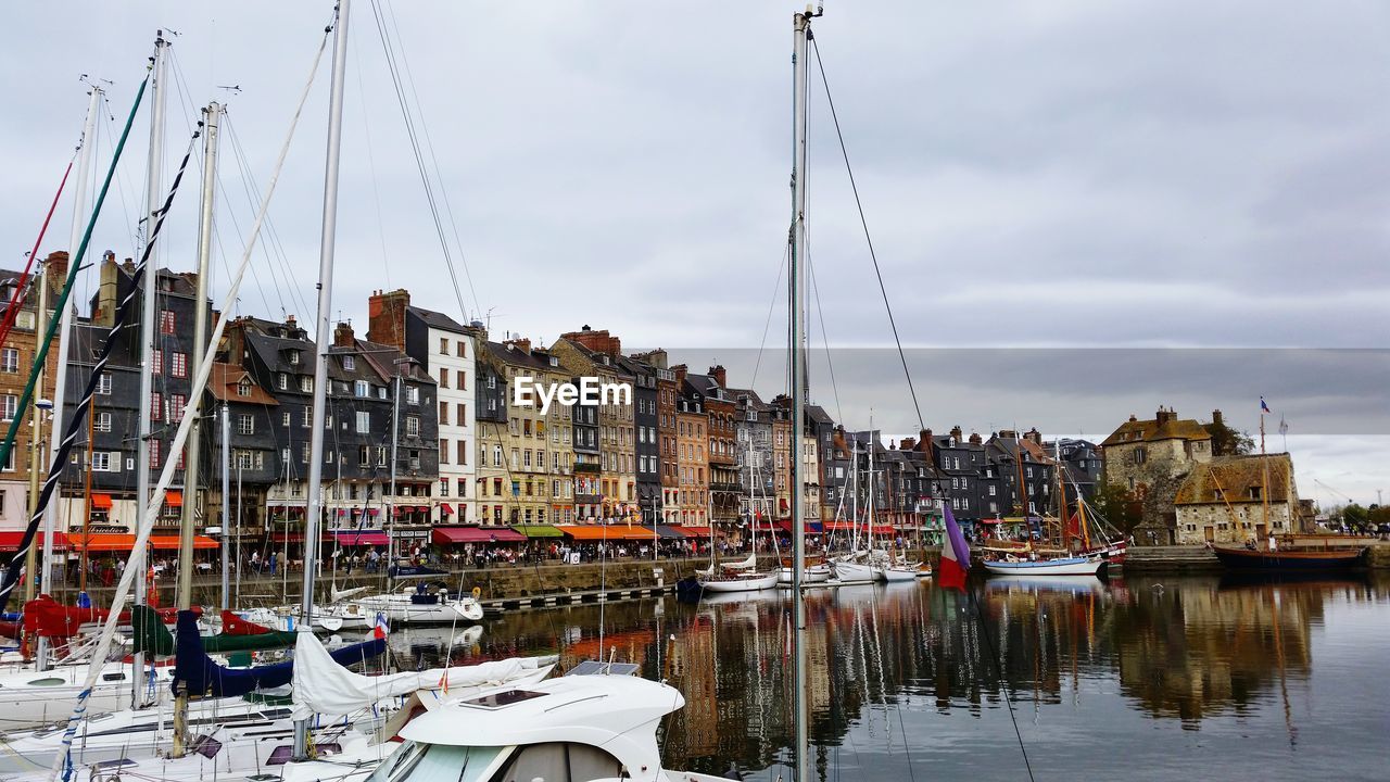 Boats moored in amusement park by city against sky