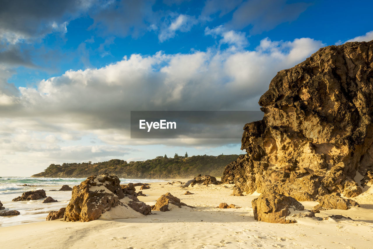 ROCK FORMATION ON BEACH AGAINST SKY