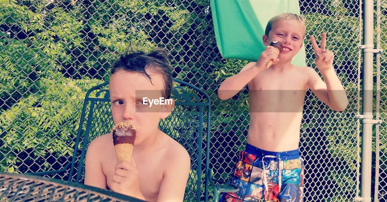 Shirtless siblings eating ice creams