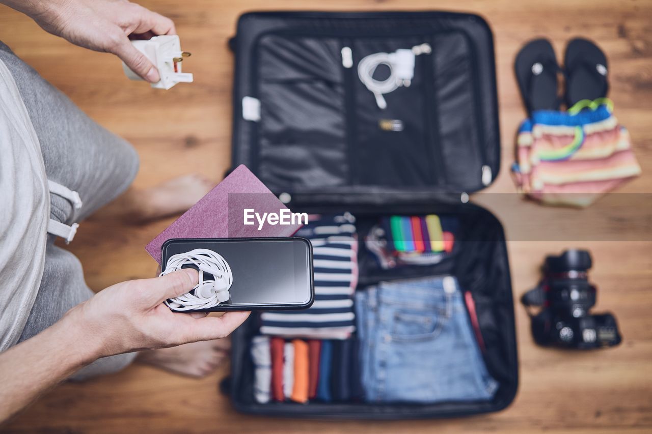 Low section of man packing luggage at home