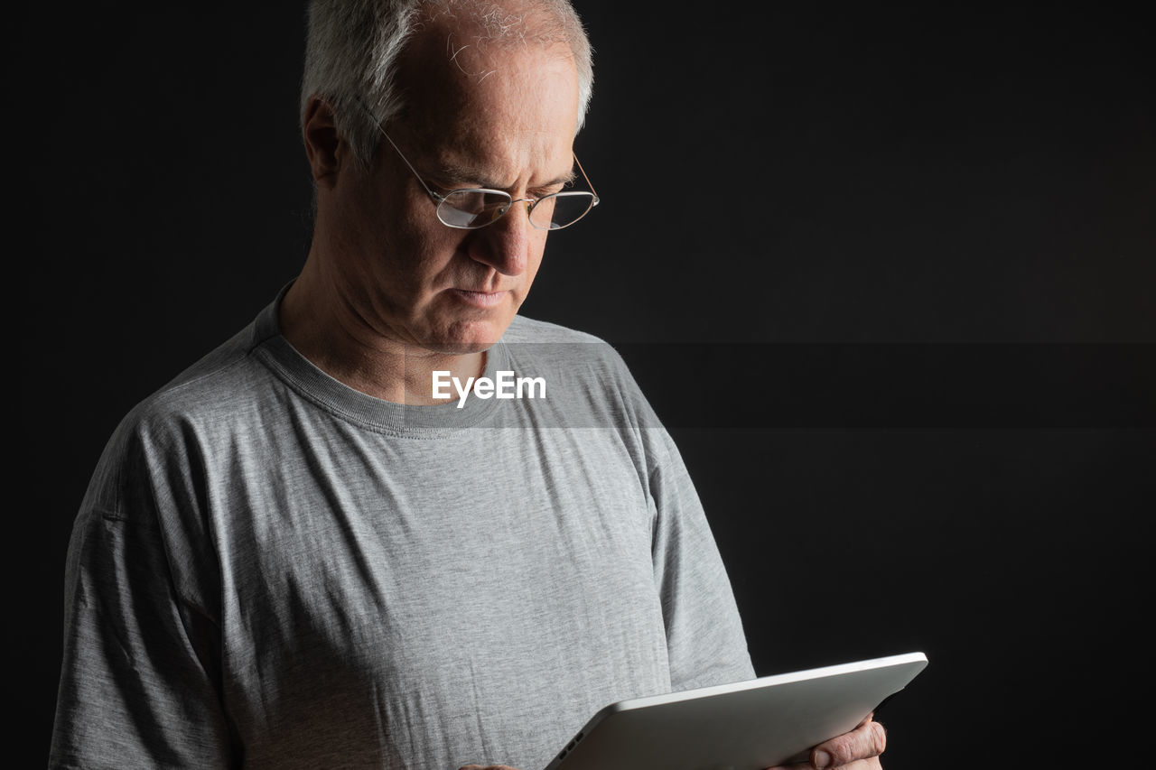 Midsection of man using digital tablet against black background