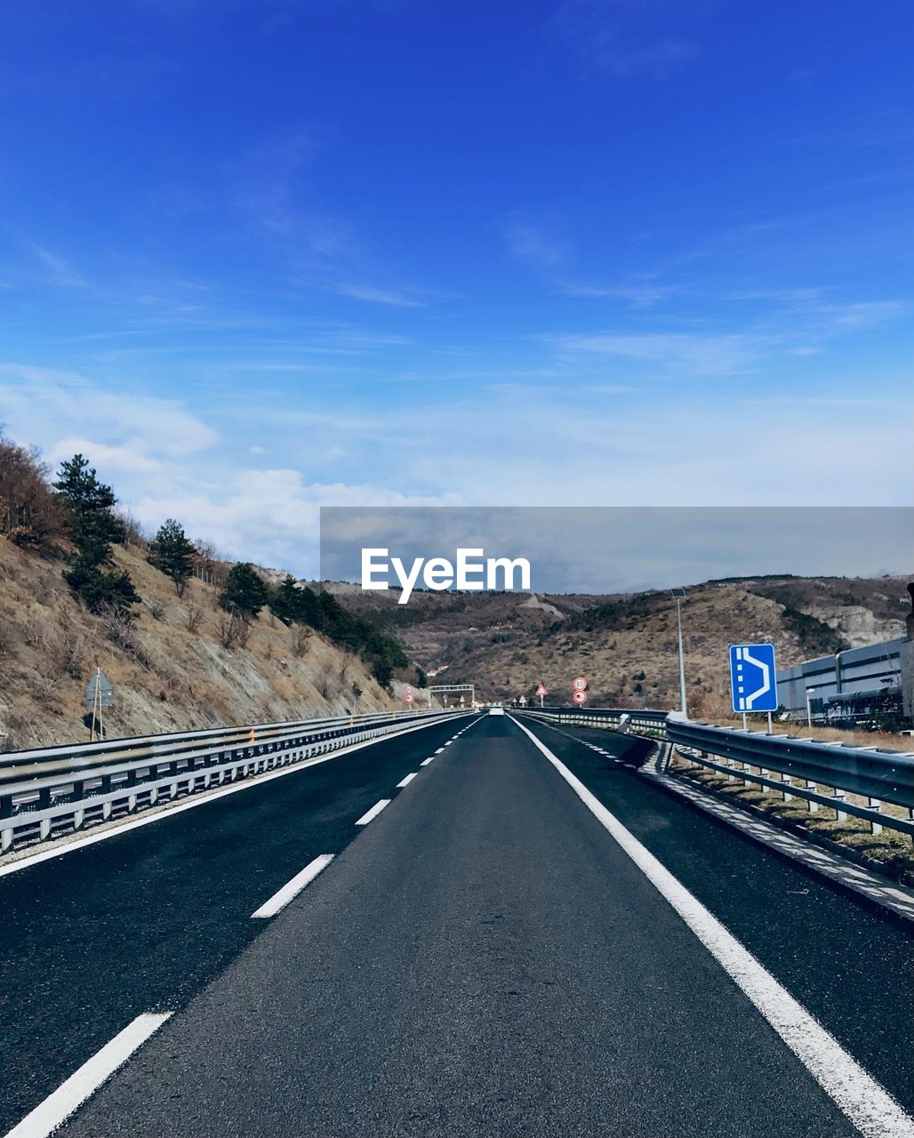 Road leading towards mountain against blue sky