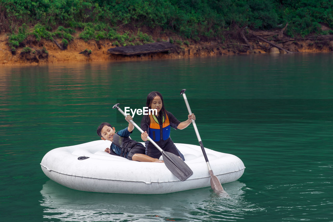 Cute girl and boy sitting on boat in lake
