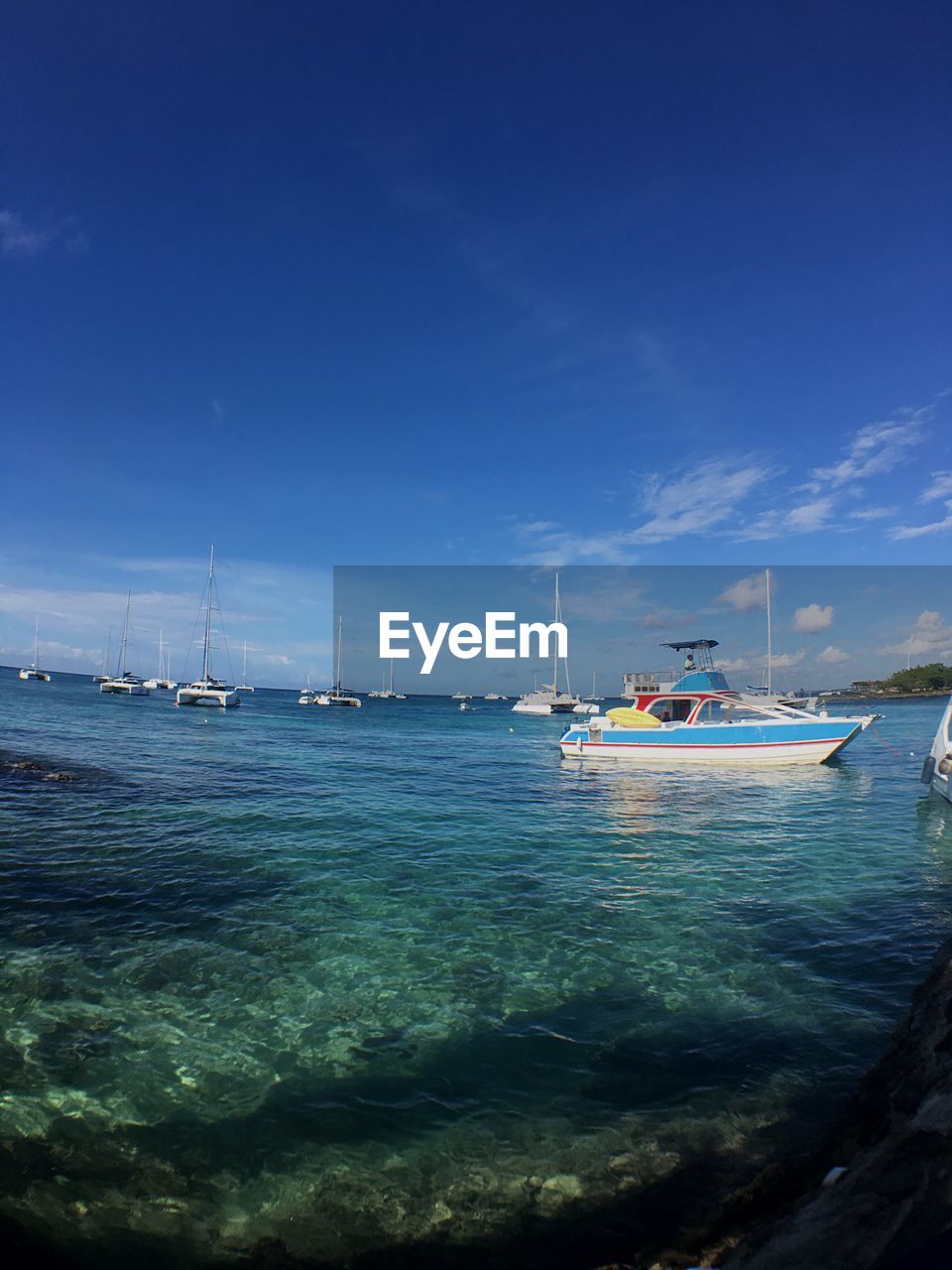 SAILBOATS MOORED IN SEA AGAINST SKY
