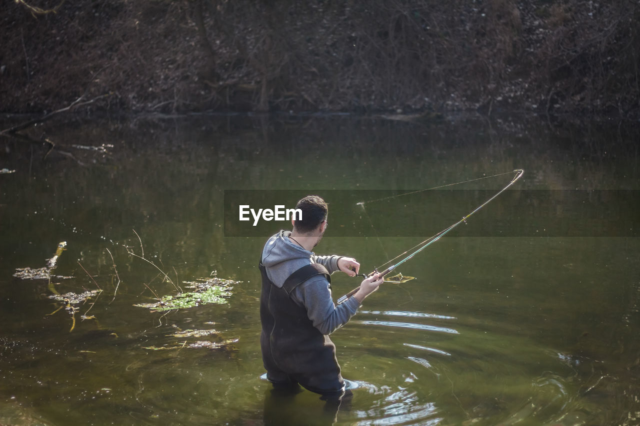 MAN FISHING IN RIVER WITH WATER