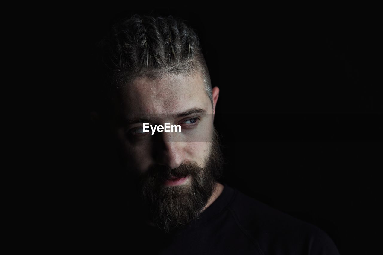 Thoughtful man looking away against black background