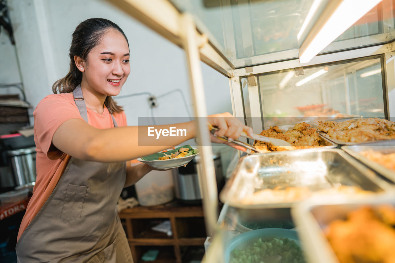 portrait of smiling young woman preparing food at home