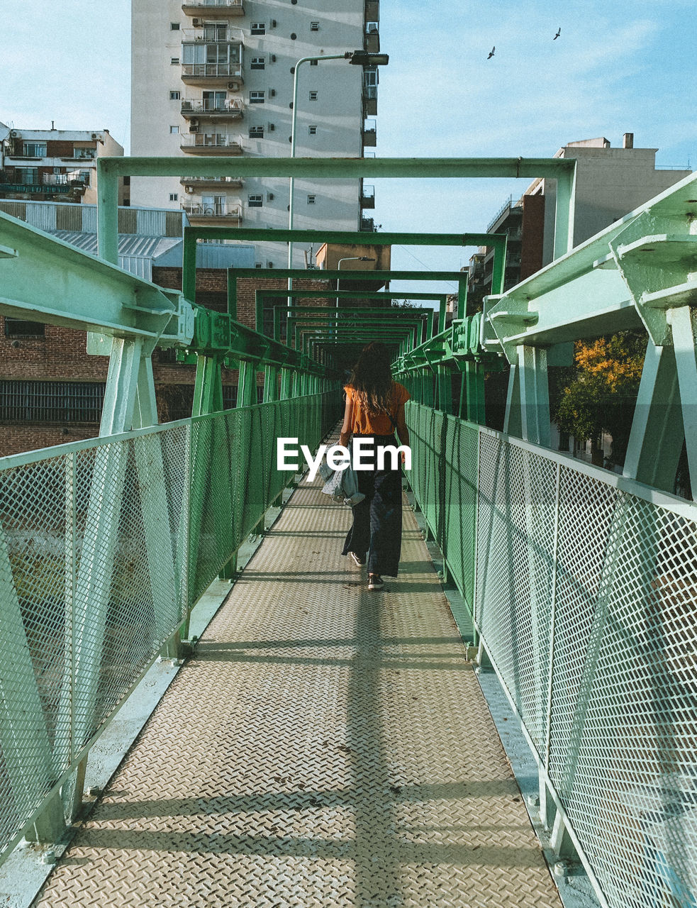 Woman walking on footbridge in city