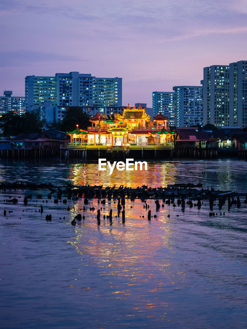 River and illuminated buildings in city at dusk