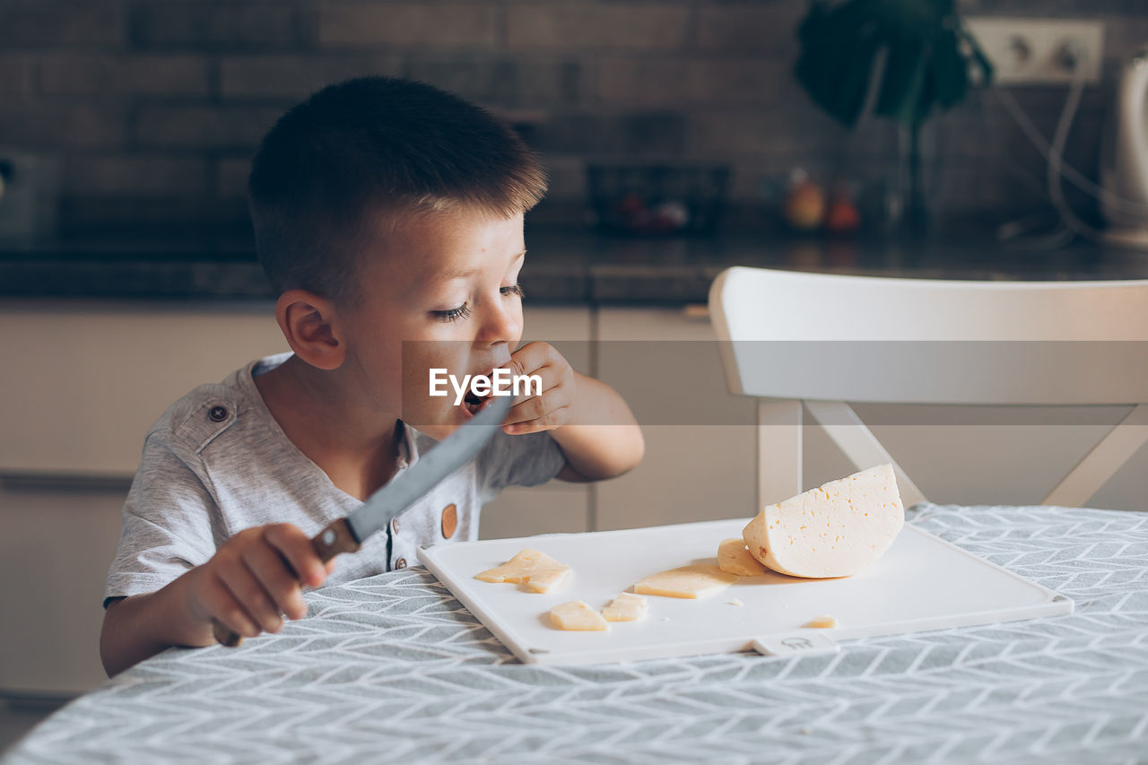 HIGH ANGLE VIEW OF BOY EATING FOOD AT TABLE