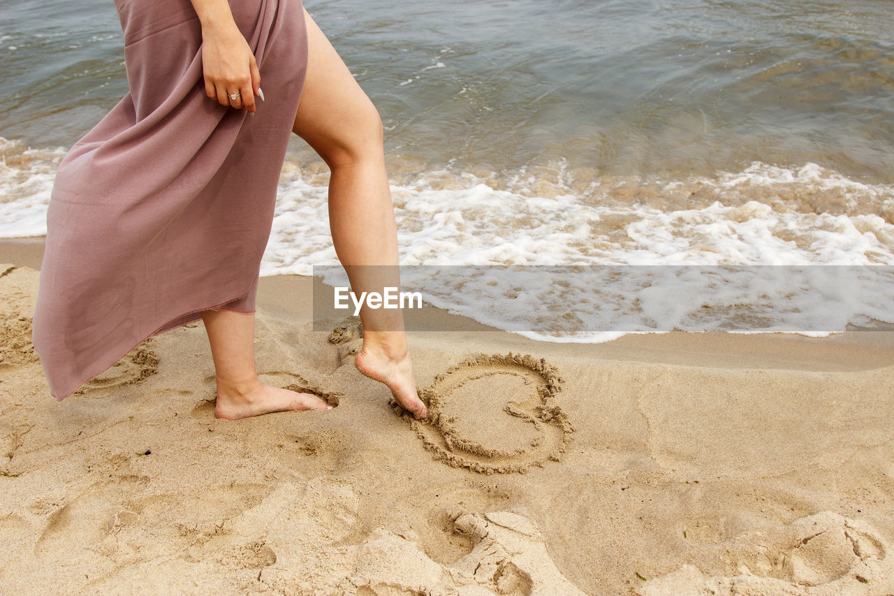 LOW SECTION OF WOMAN ON BEACH