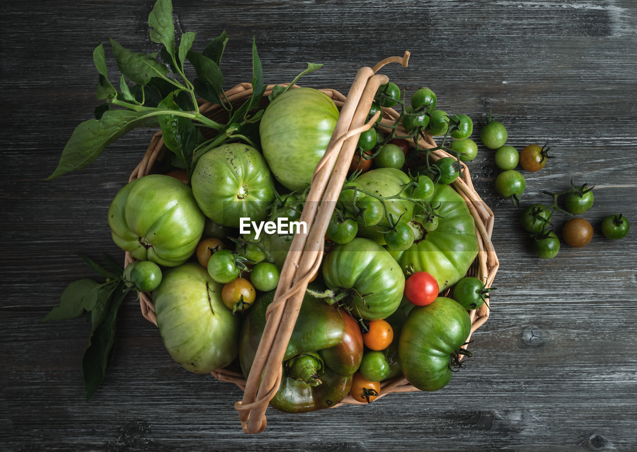 Basket of freshly harvested green tomatoes and bell peppers/