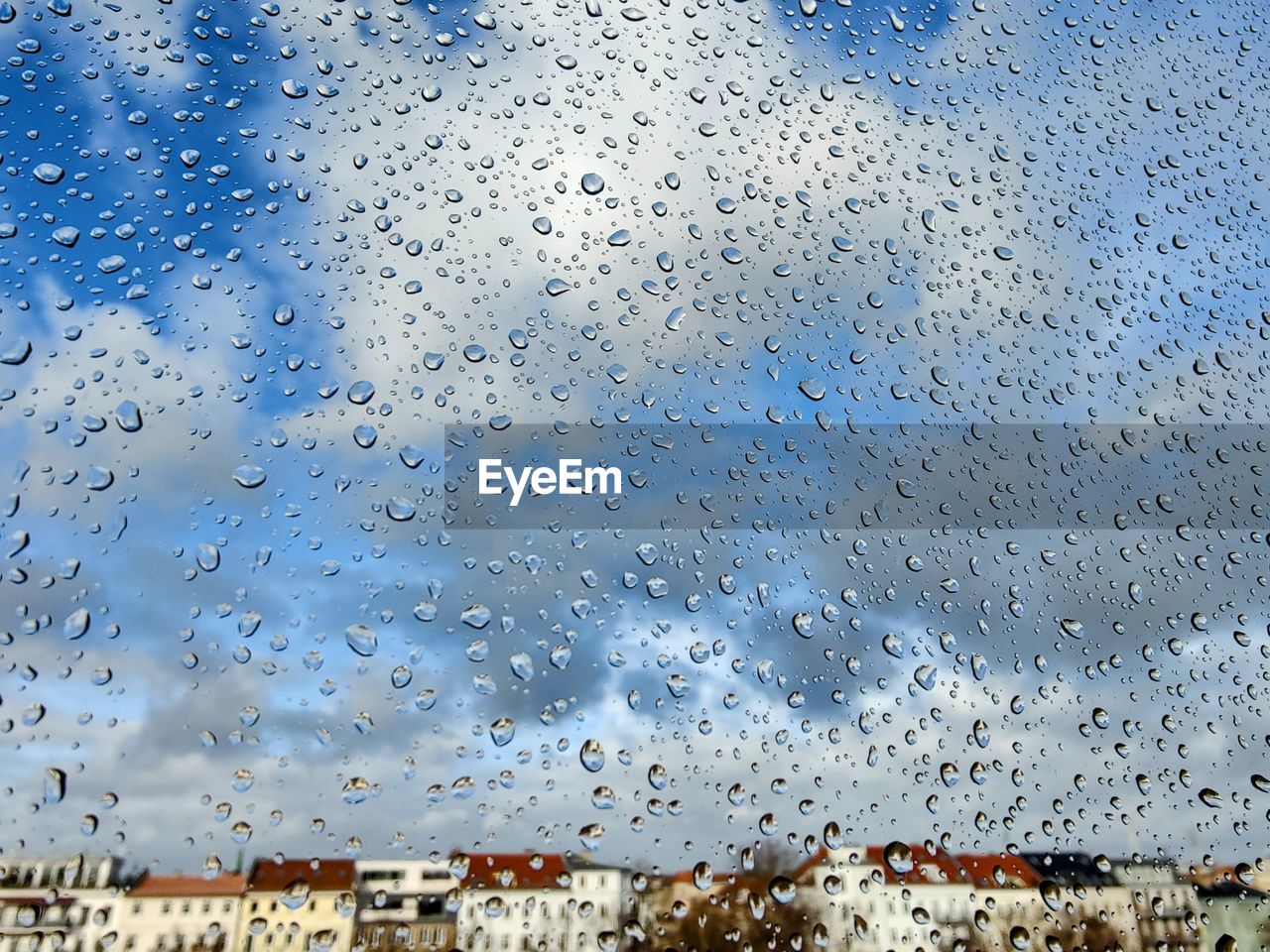 Full frame shot of wet glass window with cityscape in the background 