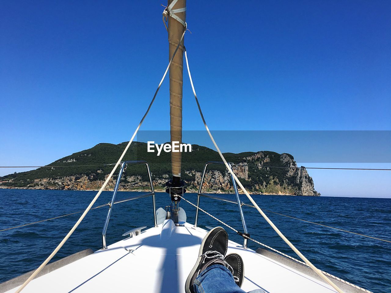 Sailboat sailing on sea against clear blue sky