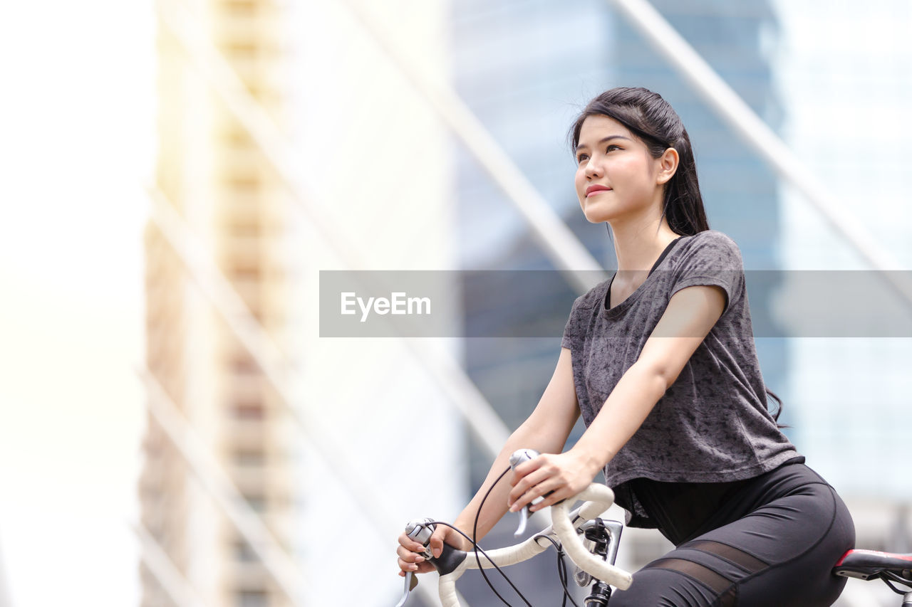 Young woman looking away while sitting on bicycle