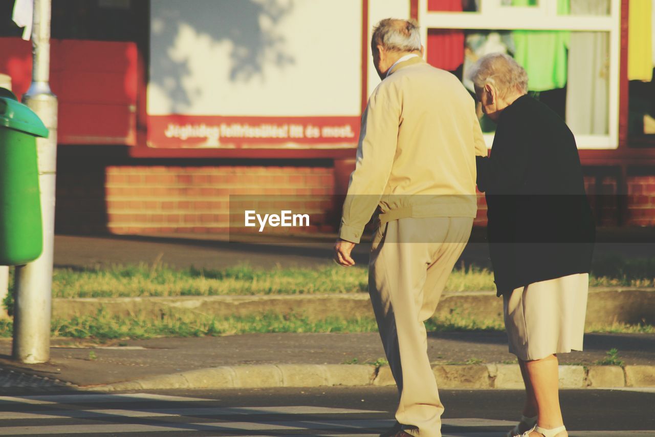 REAR VIEW OF COUPLE WALKING ON STREET