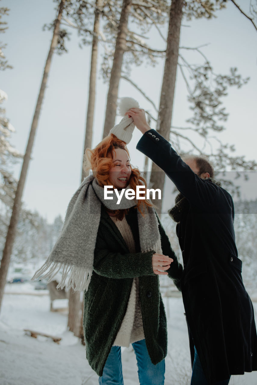 Smiling couple dancing while standing during winter in forest