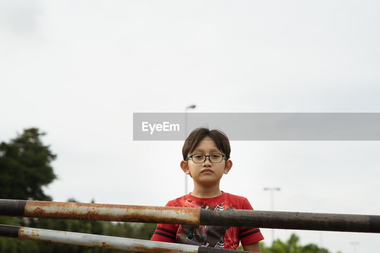 Low angle portrait of boy against clear sky