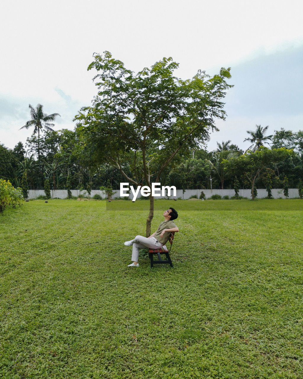 Man relaxing on bench against sky