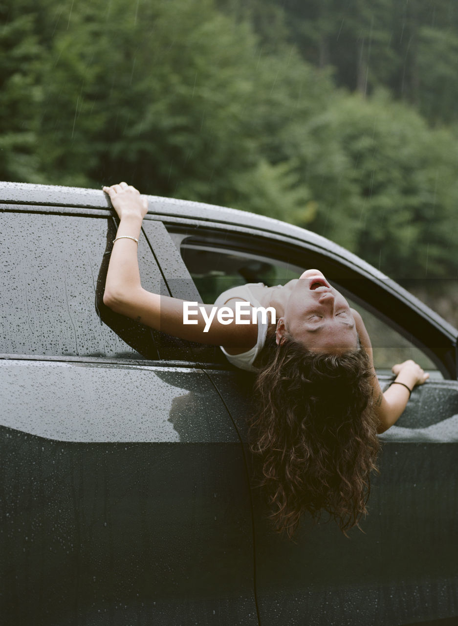 PORTRAIT OF WOMAN IN CAR AGAINST TREES