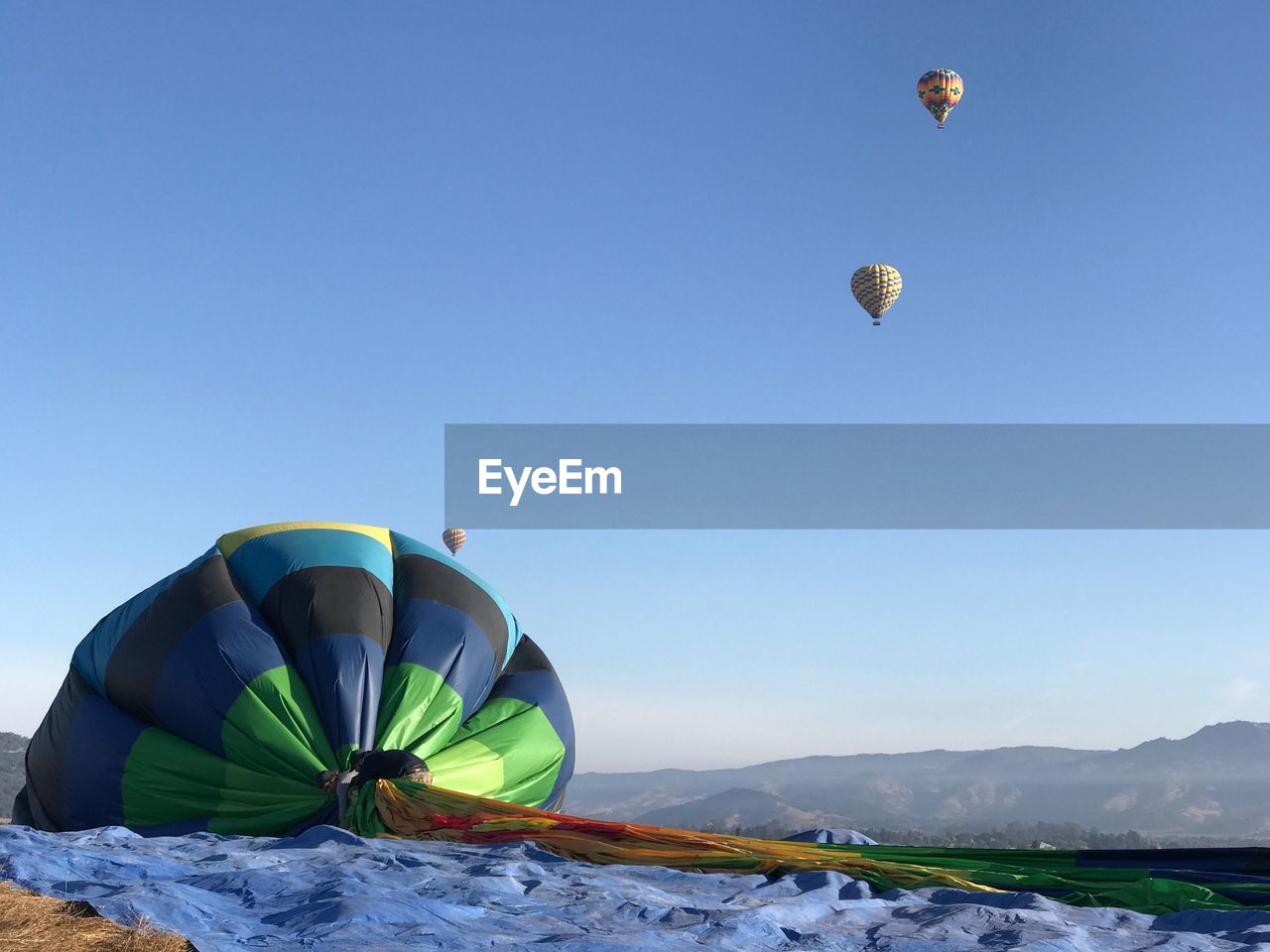 Men with hot air balloon on mountain against clear sky