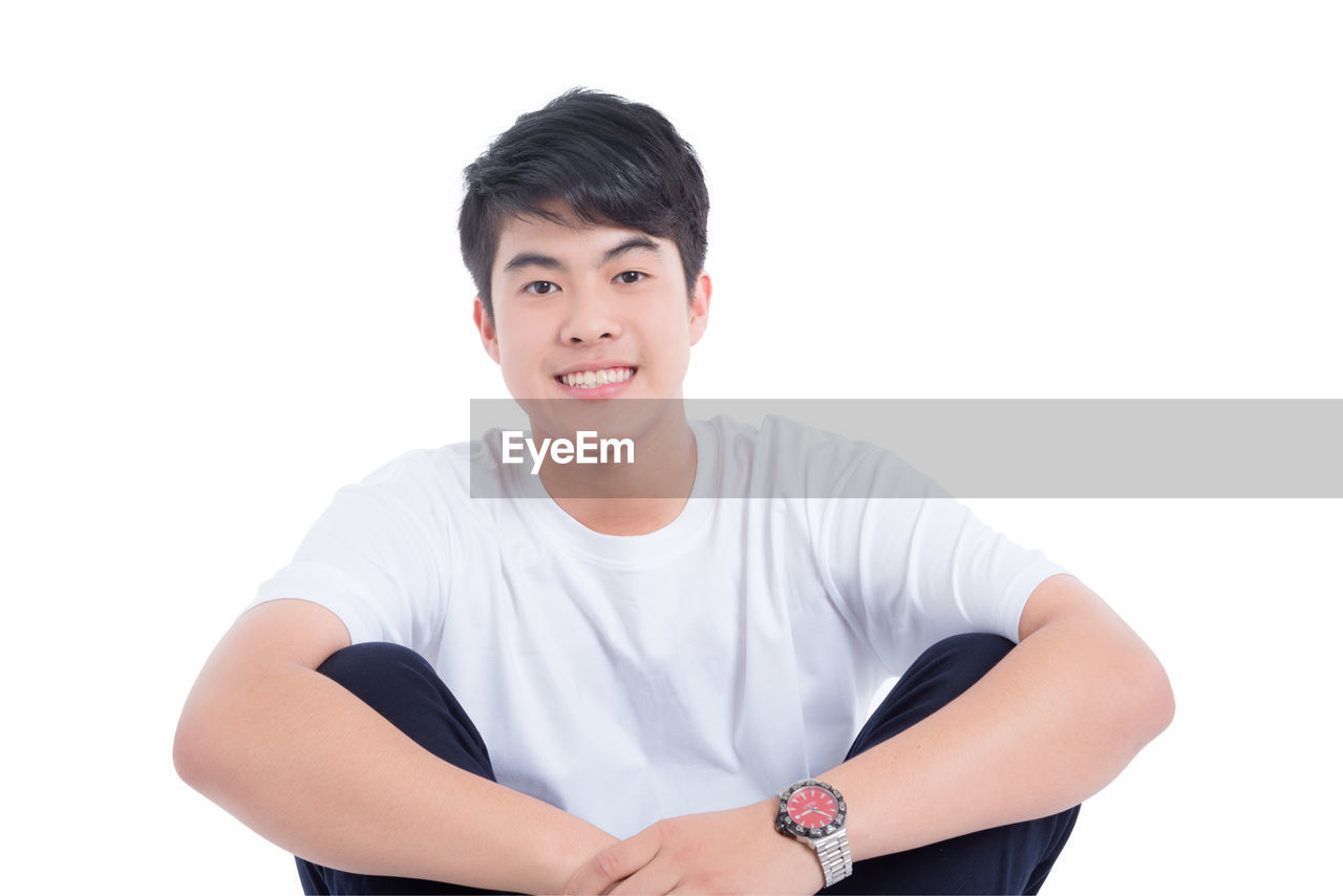 PORTRAIT OF SMILING MAN STANDING AGAINST WHITE BACKGROUND