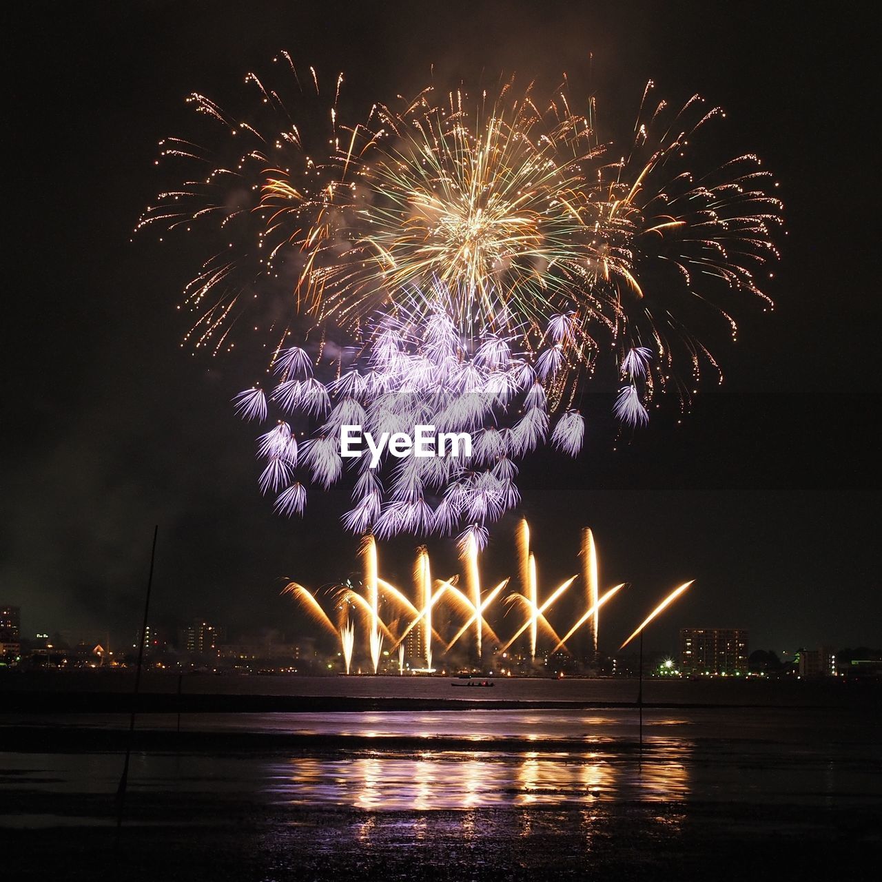 Low angle view of multi colored fireworks above river at night