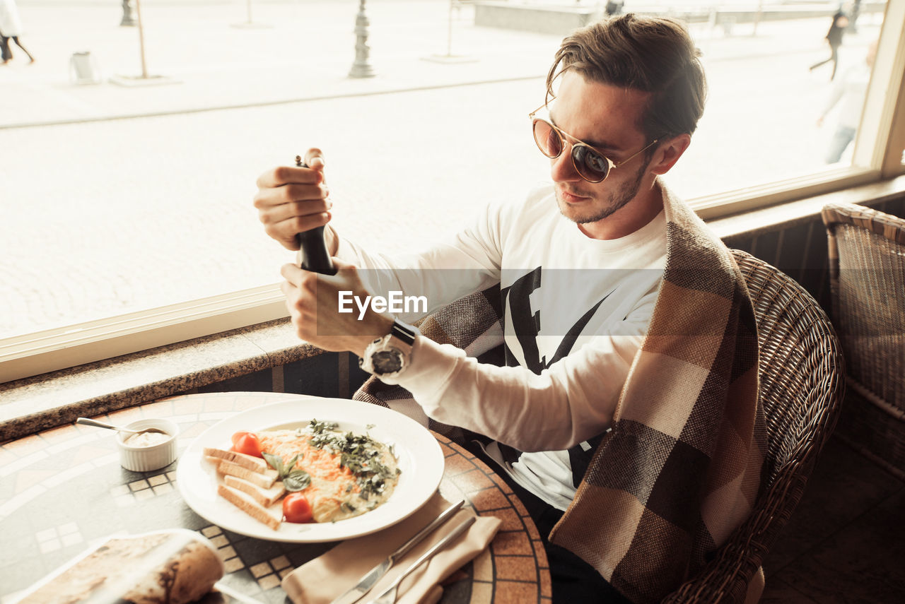 High angle view of man using pepper grinder in restaurant