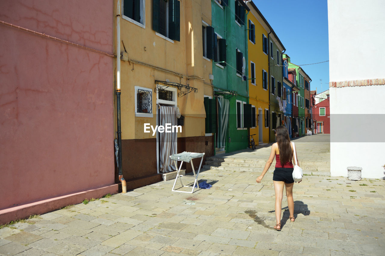 WOMAN WITH UMBRELLA WALKING ON COBBLESTONE