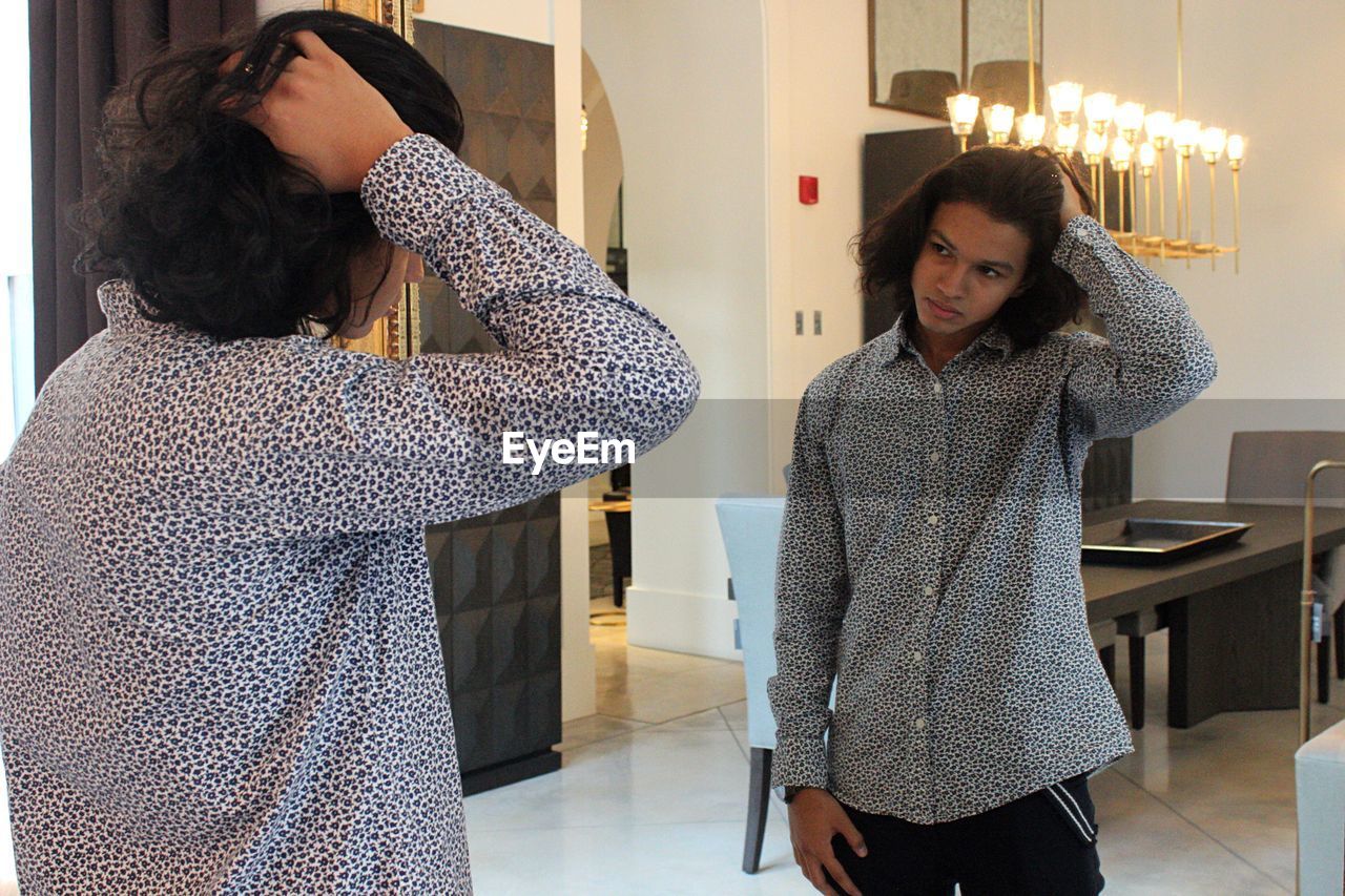 Young man with hand in hair looking at mirror