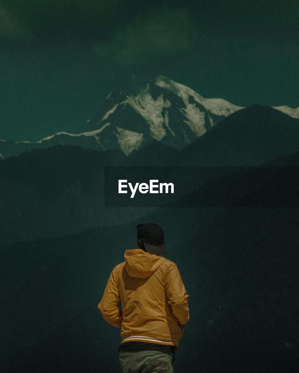 Rear view of man standing on snowcapped mountain against sky