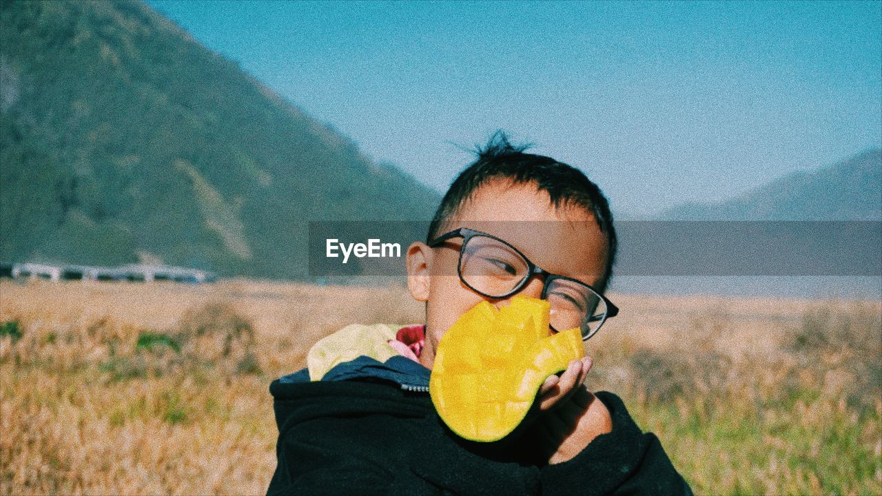 Portrait of child wearing mask on field against sky