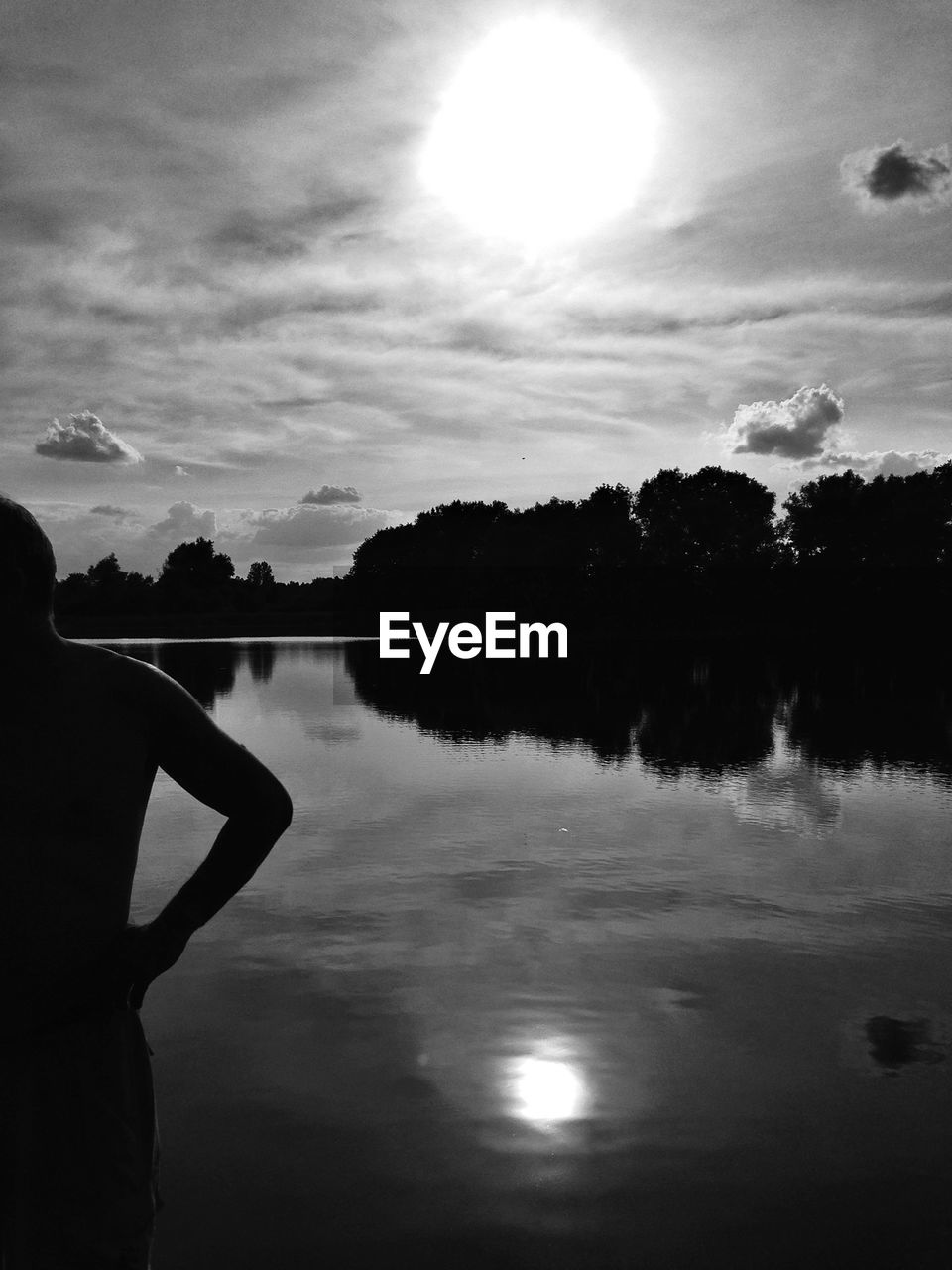 Cropped image man by lake against sky