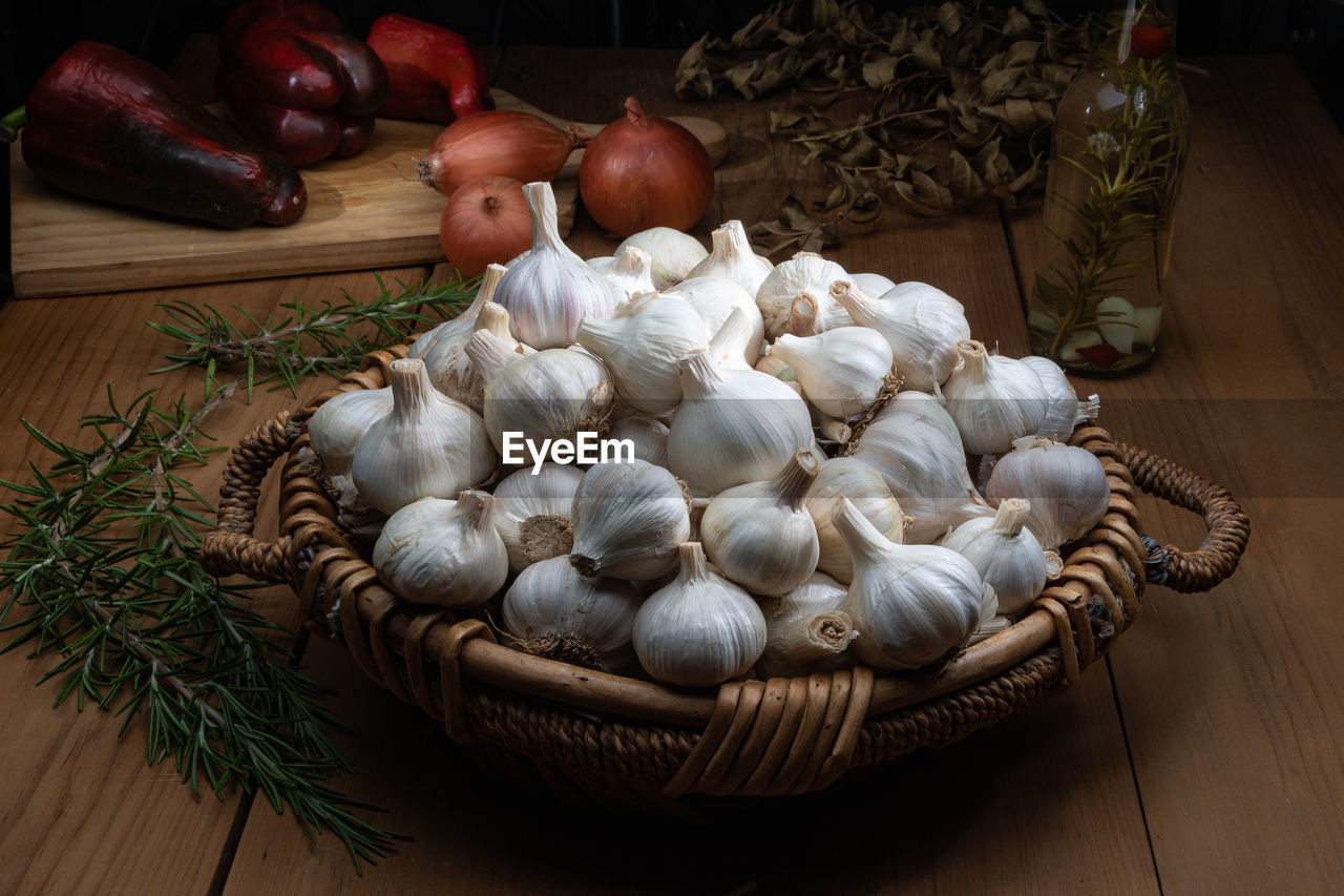 food, food and drink, vegetable, garlic, freshness, healthy eating, indoors, wellbeing, ingredient, produce, wood, spice, no people, onion, high angle view, mushroom, garlic bulb, large group of objects, still life, table, plant, basket, edible mushroom, raw food, abundance