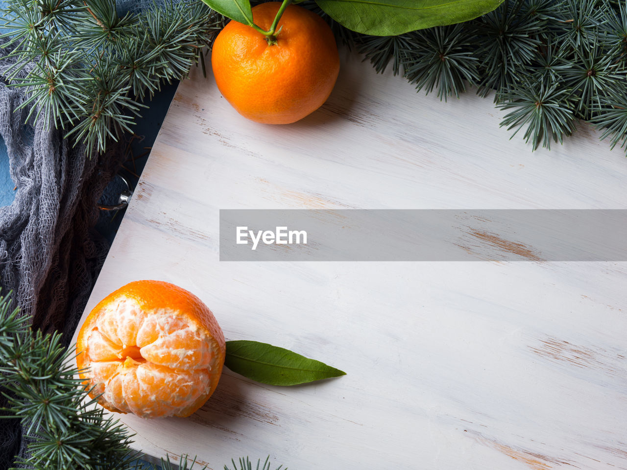 Winter tangerines frame on white rustic wooden board with spruce branches