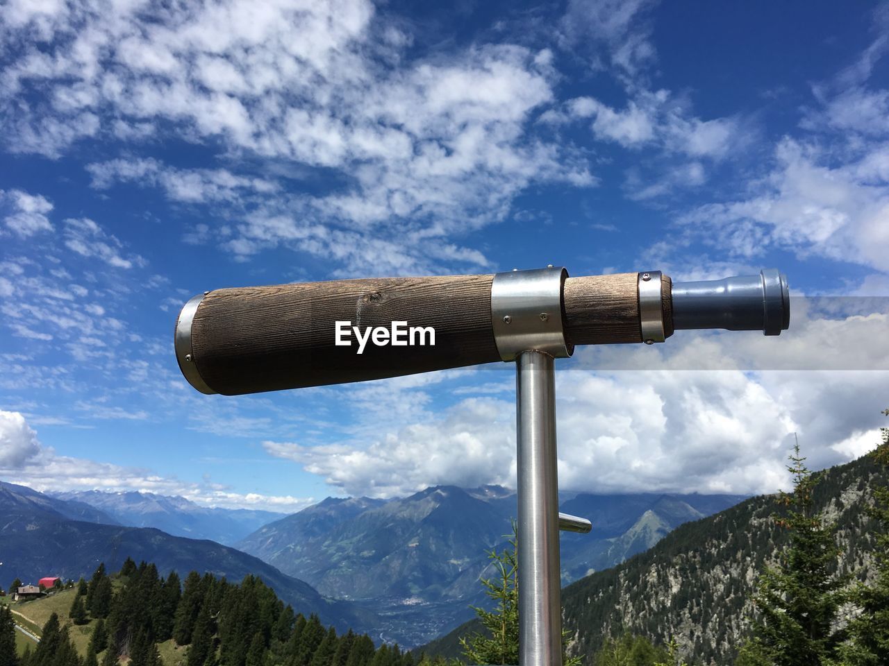 Low angle view of coin-operated binoculars by mountains against sky