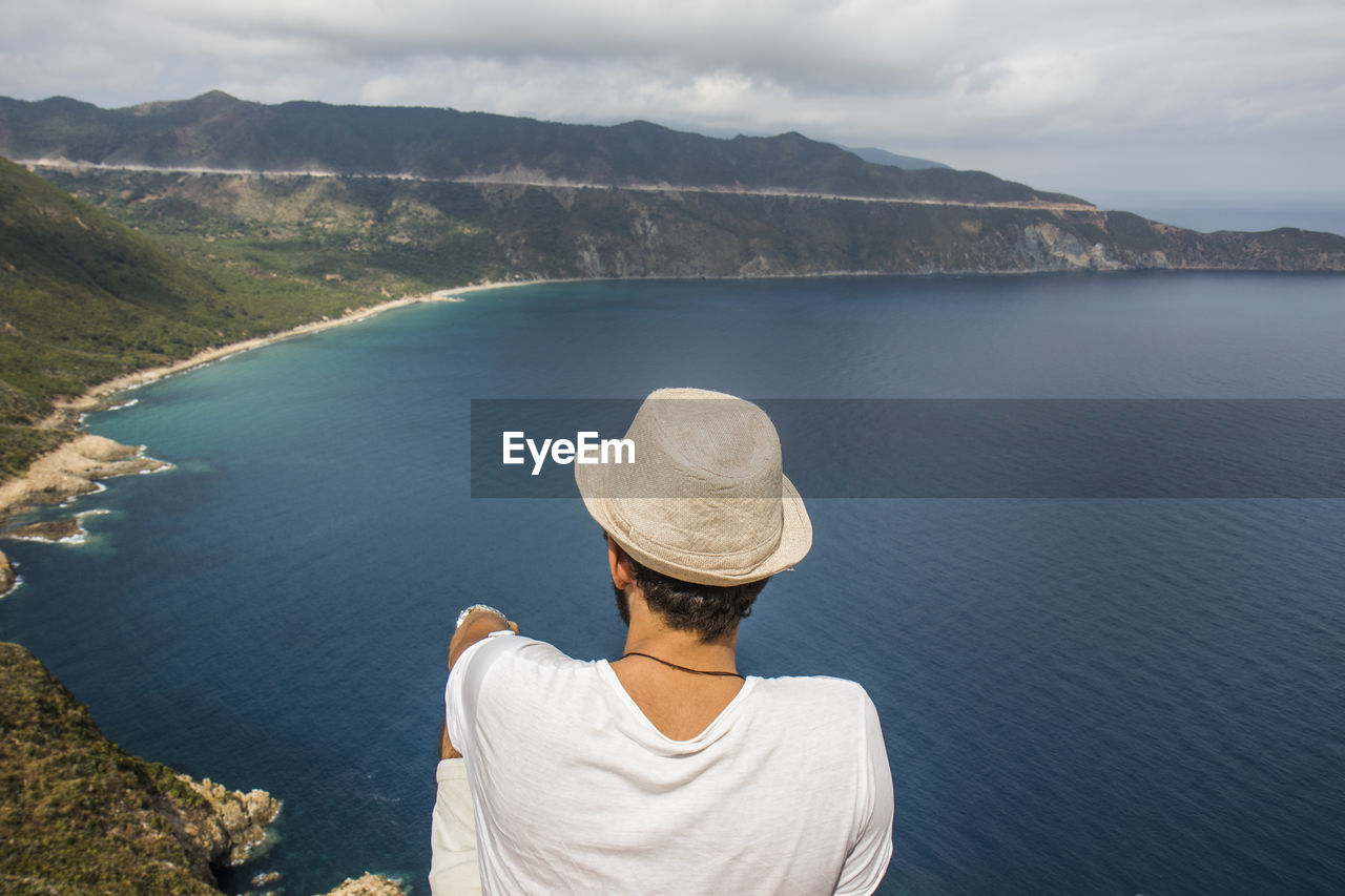 Rear view of man on lake against mountain range
