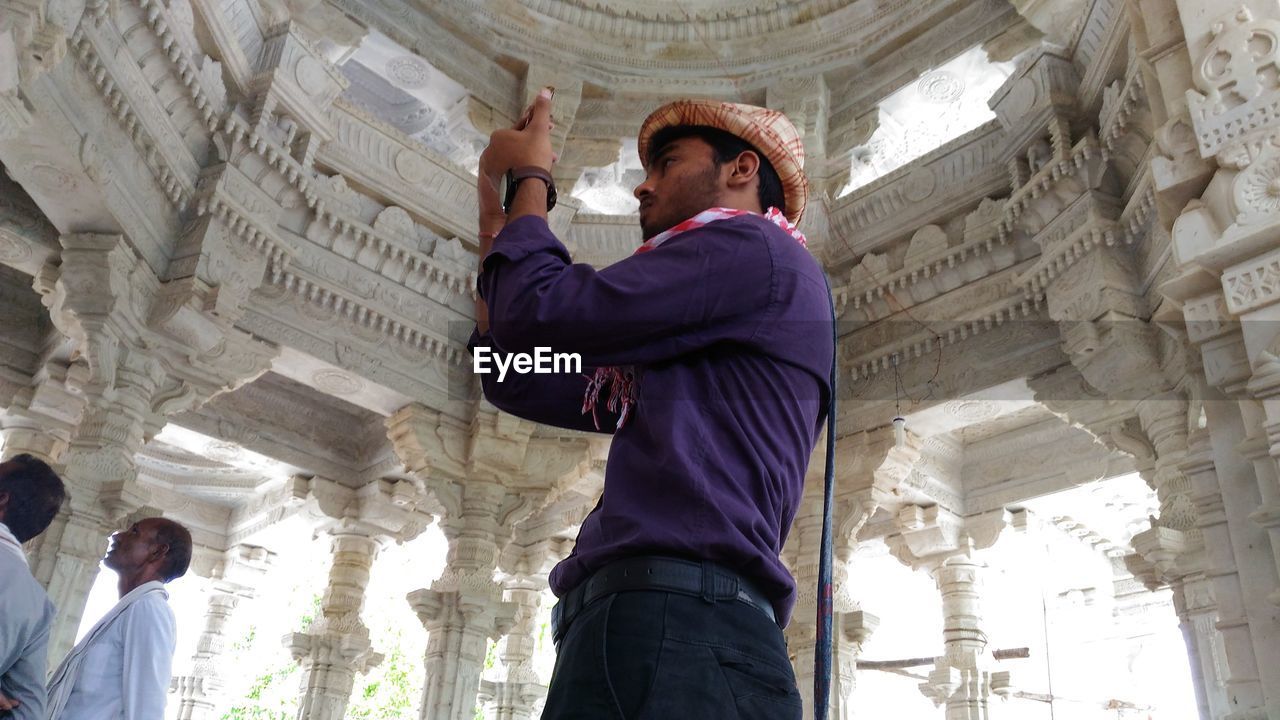 Low angle view of man photographing at temple