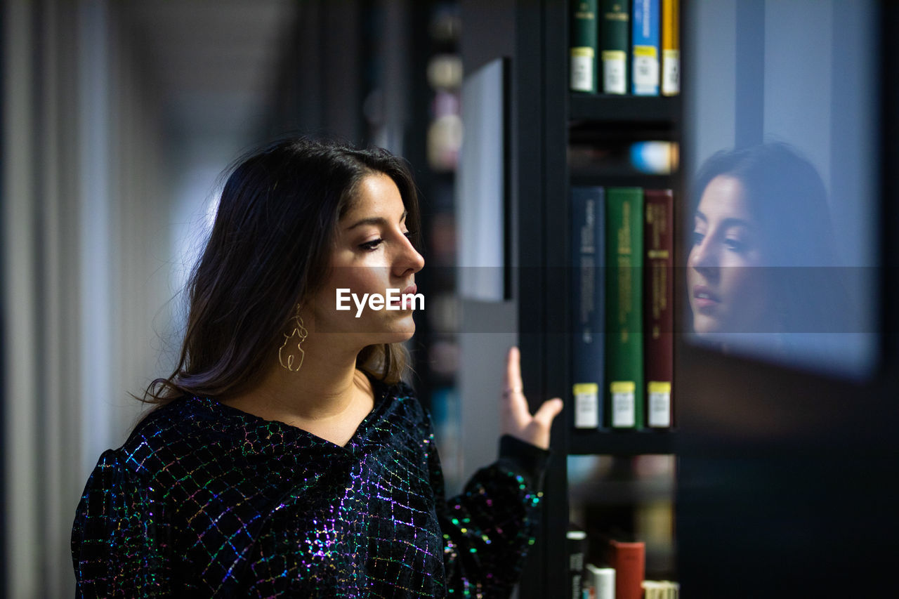 Young woman looking away while standing in library