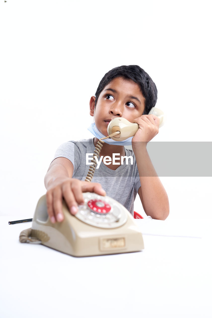 Schoolboy talking on the telephone during online class at home