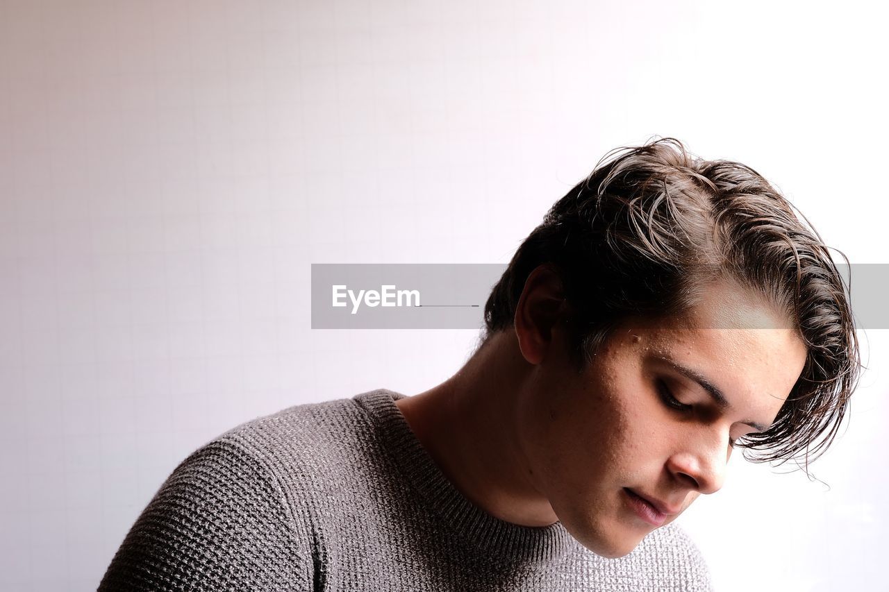 Thoughtful young man looking away against white background