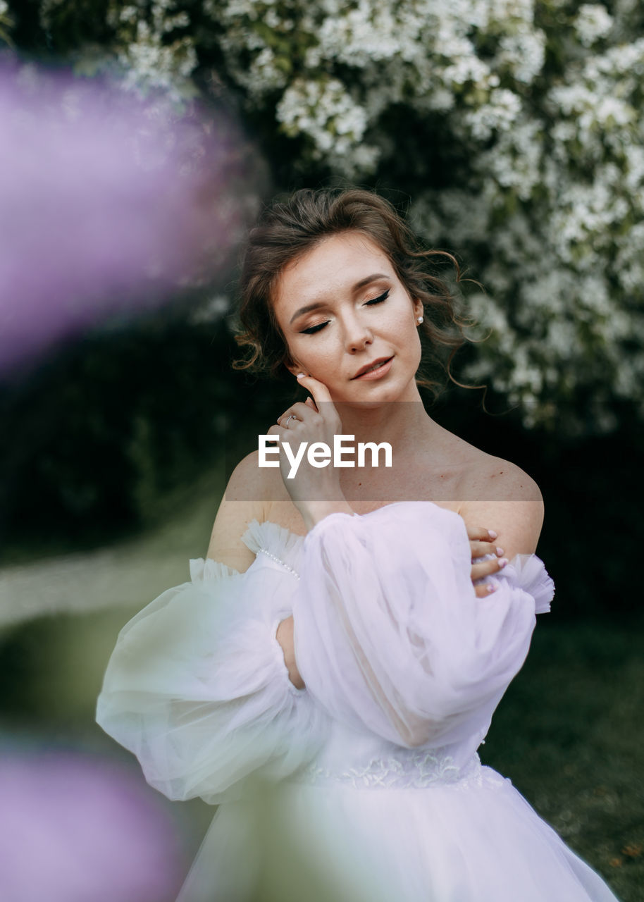 A beautiful delicate elegant woman bride in a wedding dress walks alone in a spring outdoor park