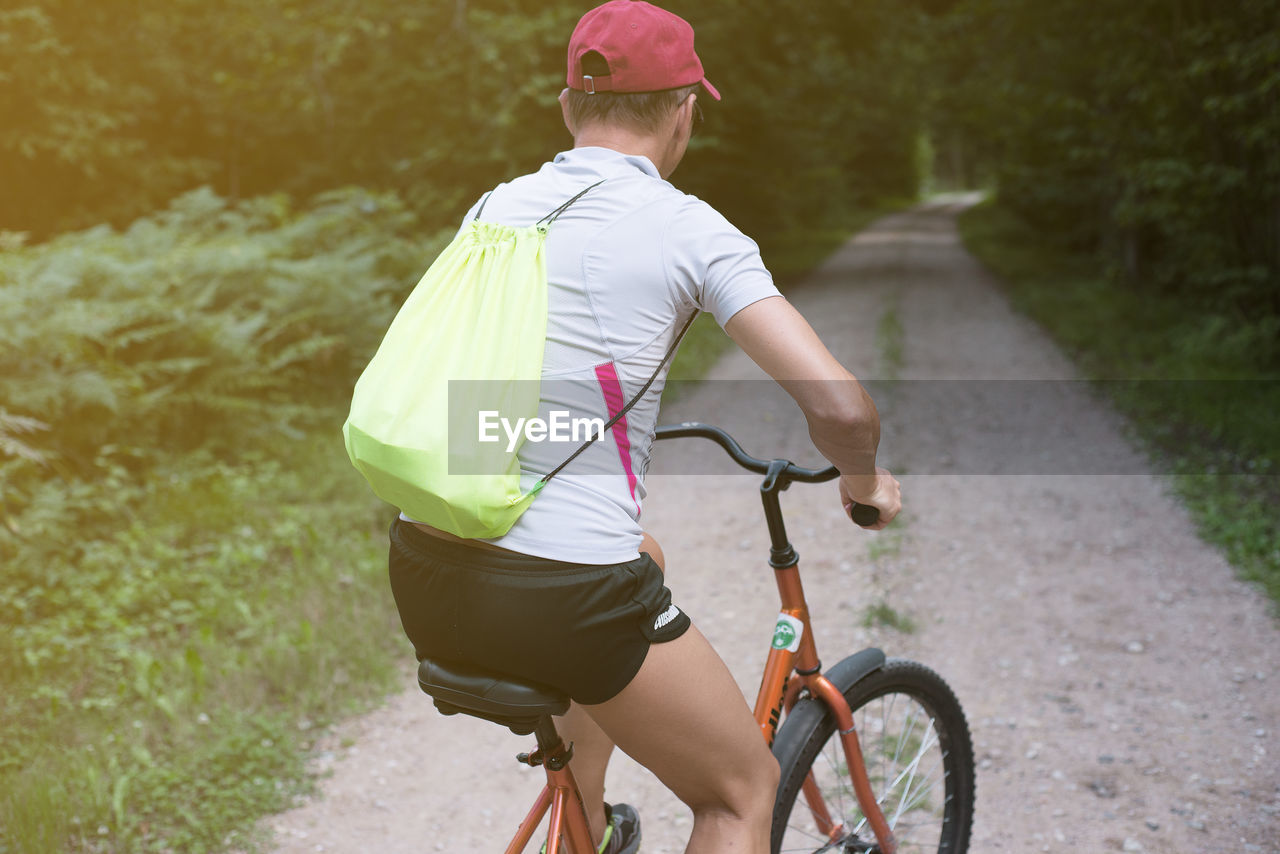 Rear view of man riding bicycle on road